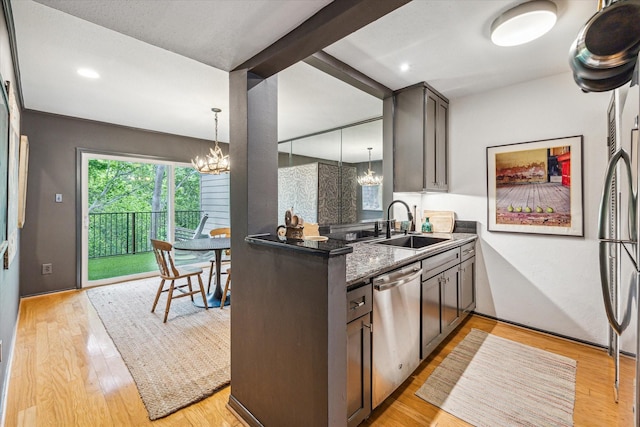 kitchen with a chandelier, stainless steel dishwasher, light wood-style flooring, and a sink