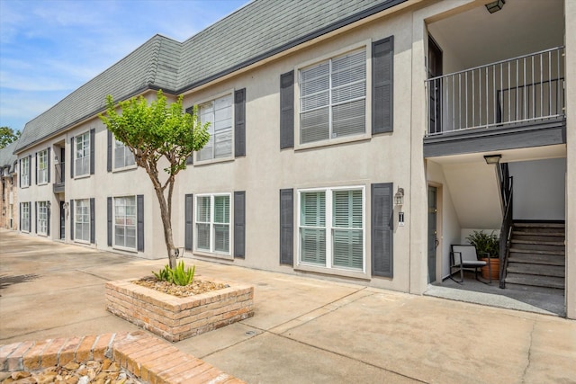 back of property with a balcony, stucco siding, and a patio