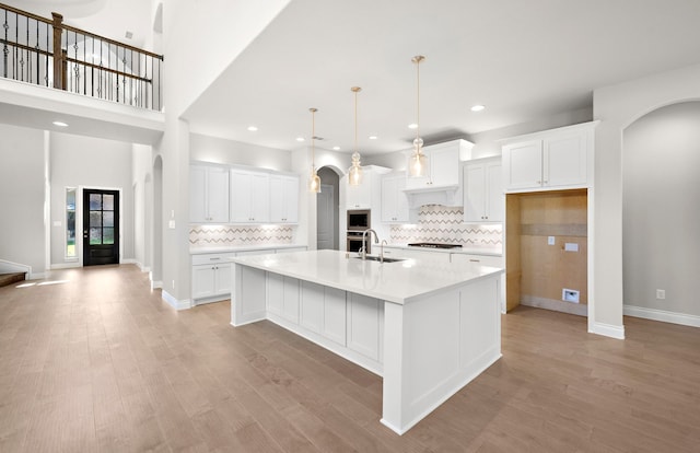 10719 Jacobina Ct, Cypress, TX 77433 - kitchen featuring white cabinetry, arched walkways, gas cooktop, and a sink
