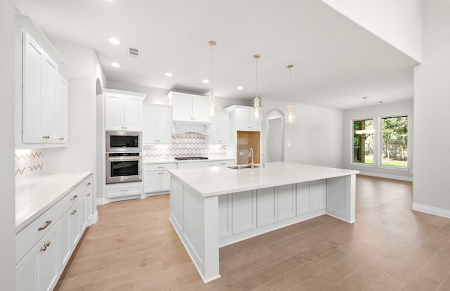 10719 Jacobina Ct, Cypress, TX 77433 - kitchen with decorative backsplash, a sink, appliances with stainless steel finishes, visible vents, and light wood finished floors