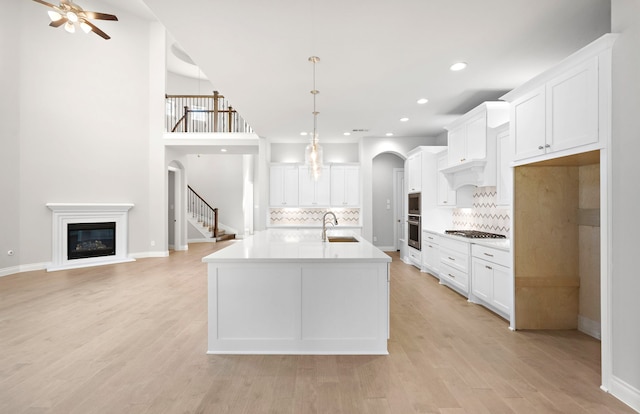 10719 Jacobina Ct, Cypress, TX 77433 - kitchen with decorative backsplash, a sink, stainless steel appliances, and a glass covered fireplace