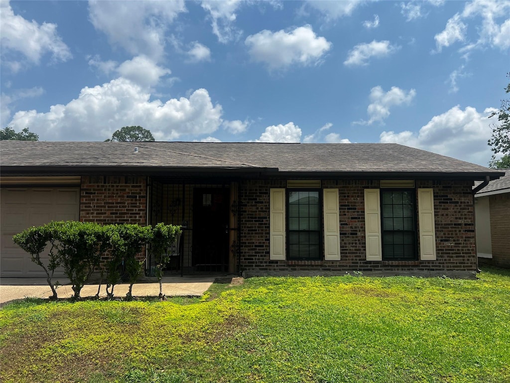 view of front of house featuring a front lawn, brick siding, and an attached garage