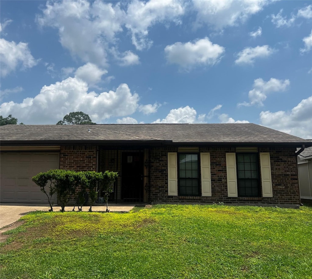 view of front of home with concrete driveway, a front yard, brick siding, and a garage