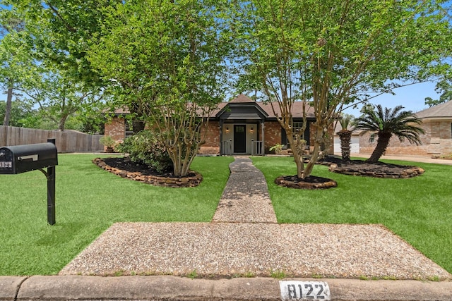 view of front of property with a front yard, brick siding, and fence