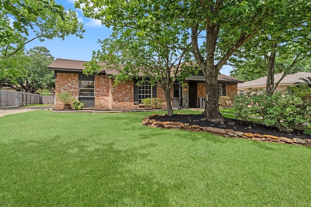 ranch-style home with brick siding, fence, and a front lawn