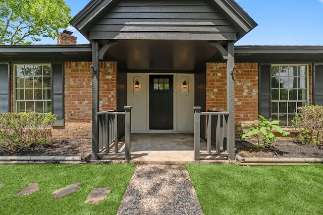 property entrance with a porch, brick siding, and a chimney