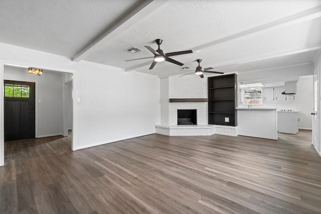 unfurnished living room featuring beam ceiling, a textured ceiling, visible vents, and a wealth of natural light