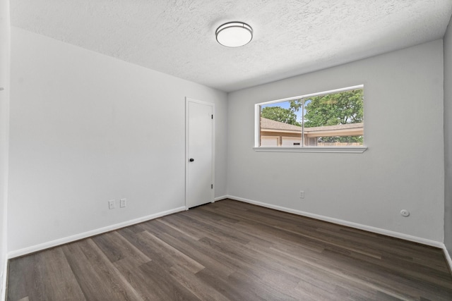 empty room featuring a textured ceiling, wood finished floors, and baseboards