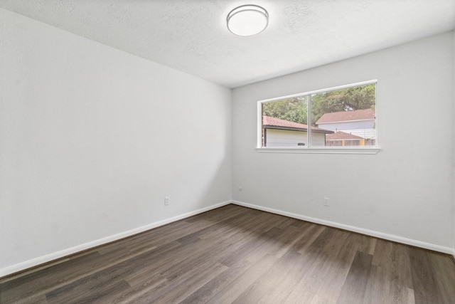 empty room featuring a textured ceiling, wood finished floors, and baseboards
