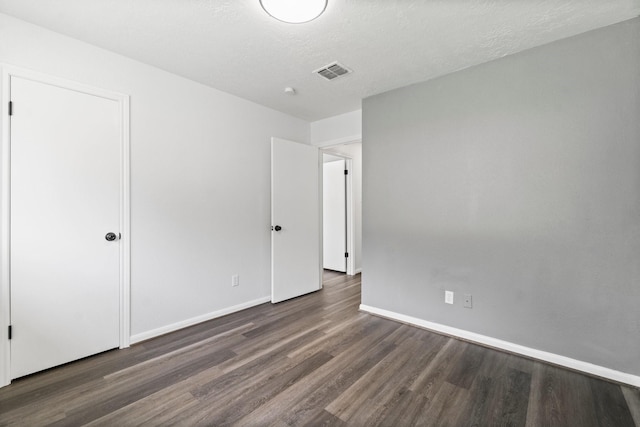 unfurnished bedroom with visible vents, wood finished floors, and baseboards