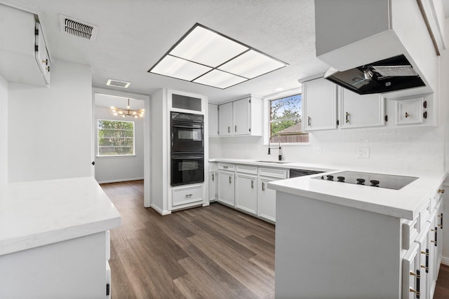 kitchen featuring a sink, visible vents, extractor fan, black appliances, and a peninsula