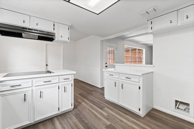 kitchen featuring black electric stovetop, under cabinet range hood, light countertops, white cabinets, and dark wood-type flooring