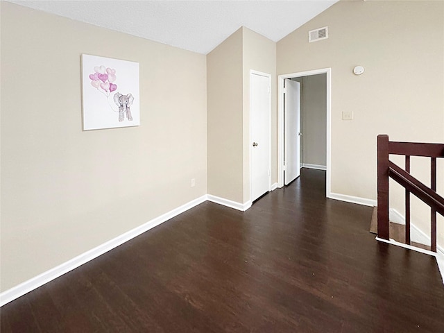 empty room featuring baseboards, visible vents, wood finished floors, and lofted ceiling