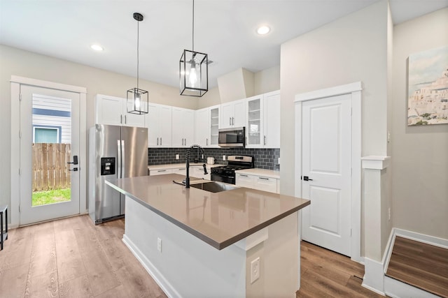 kitchen featuring tasteful backsplash, glass insert cabinets, appliances with stainless steel finishes, light wood finished floors, and a sink