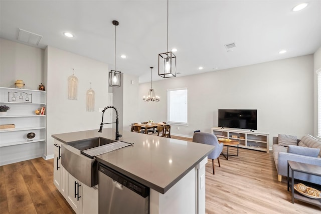 kitchen featuring stainless steel dishwasher, a sink, visible vents, open floor plan, and an island with sink