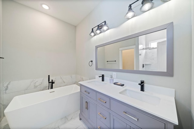 full bathroom with a soaking tub, marble finish floor, double vanity, and a sink