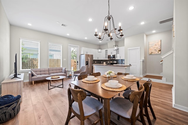 dining room featuring visible vents, light wood-style floors, a healthy amount of sunlight, and baseboards