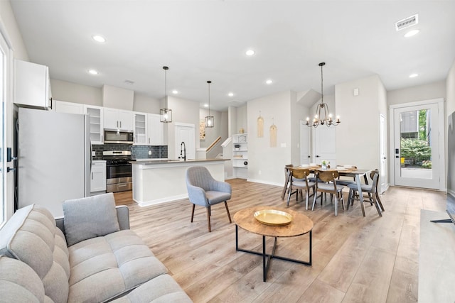living area with recessed lighting, a notable chandelier, baseboards, and light wood-style floors