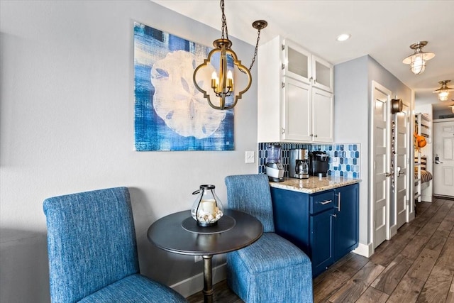 living area with baseboards, an inviting chandelier, and dark wood-style flooring