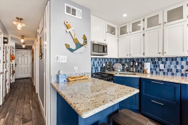 kitchen with range with electric cooktop, stainless steel microwave, a sink, visible vents, and blue cabinets