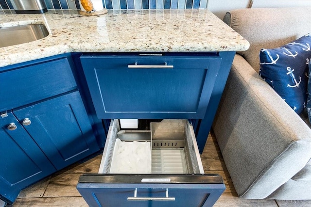 details with light stone countertops, wood finished floors, and blue cabinets