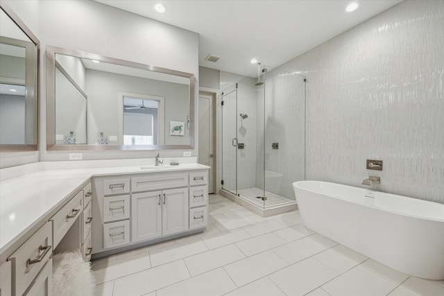 bathroom with vanity, a stall shower, a freestanding bath, visible vents, and tile patterned flooring