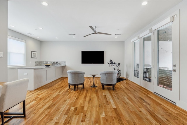 sitting room with light wood-type flooring, visible vents, ceiling fan, and a healthy amount of sunlight