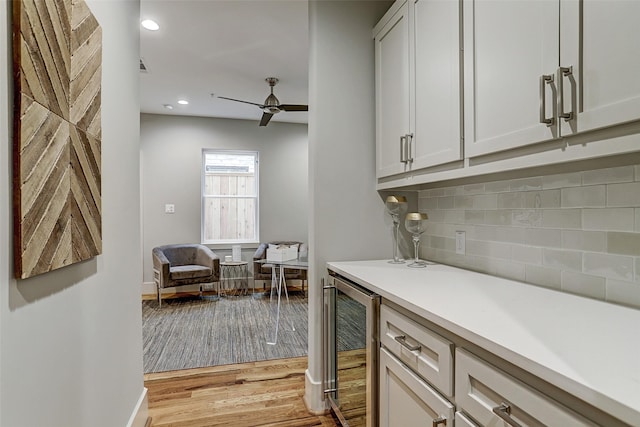 kitchen with tasteful backsplash, beverage cooler, light countertops, ceiling fan, and light wood-type flooring