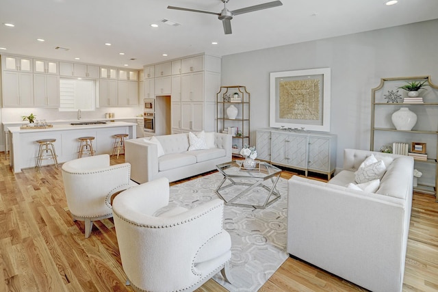 living room with light wood-style floors, a ceiling fan, visible vents, and recessed lighting