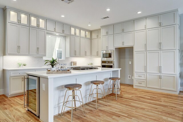 kitchen with wine cooler, stainless steel appliances, light wood-type flooring, and visible vents
