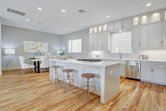 kitchen featuring stainless steel dishwasher, visible vents, a kitchen island, gas cooktop, and light wood finished floors