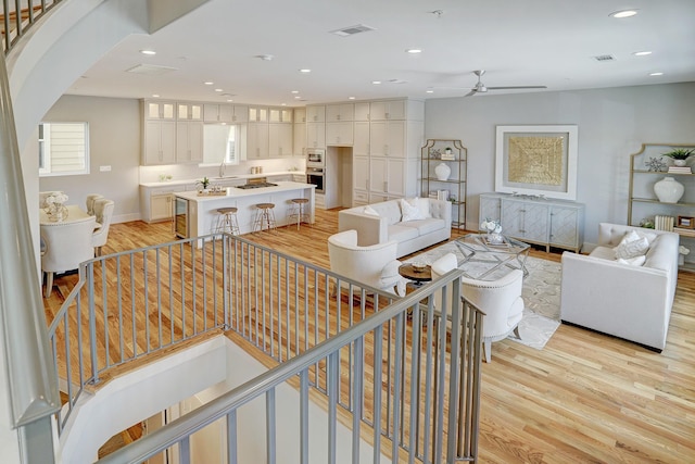 living room with visible vents, a ceiling fan, light wood-style floors, and recessed lighting