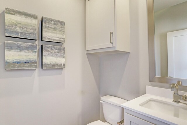 half bath featuring vanity and toilet