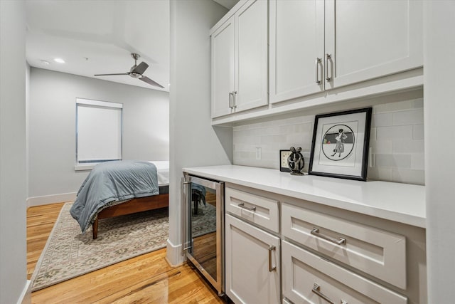 kitchen with beverage cooler, light countertops, backsplash, ceiling fan, and light wood finished floors