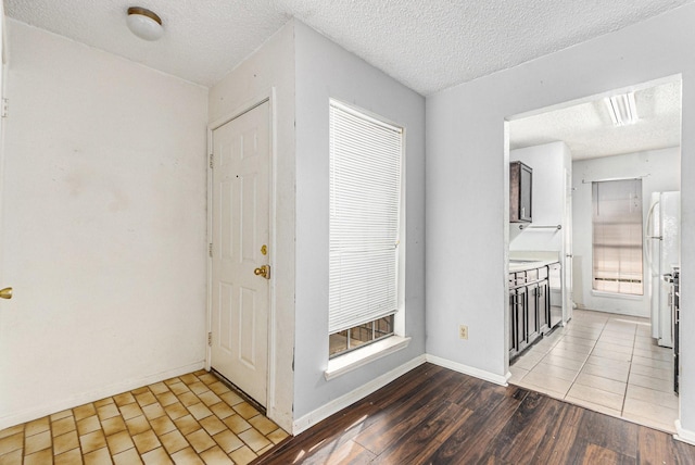 entryway featuring baseboards, wood finished floors, a healthy amount of sunlight, and a textured ceiling