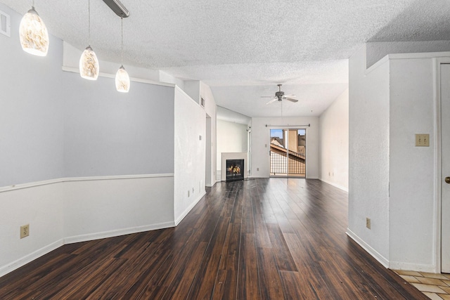 unfurnished living room featuring a textured ceiling, ceiling fan, wood finished floors, and baseboards