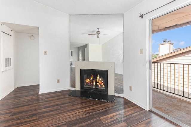 unfurnished living room featuring baseboards, wood finished floors, a ceiling fan, and a lit fireplace