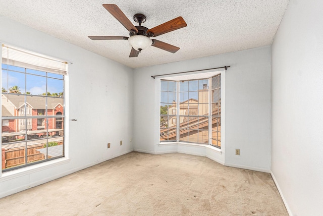 carpeted spare room with a textured ceiling, ceiling fan, and baseboards