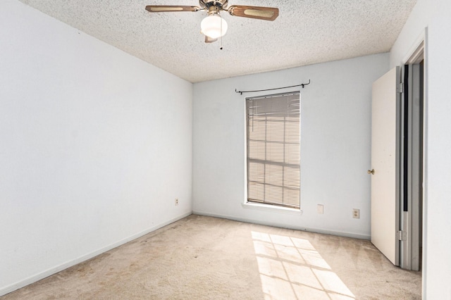carpeted empty room with a textured ceiling, ceiling fan, and baseboards