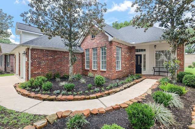 view of front of home with concrete driveway, a shingled roof, brick siding, and a garage