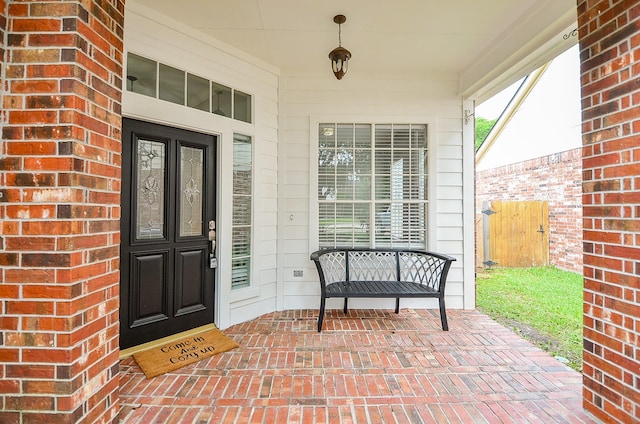 view of exterior entry featuring covered porch and brick siding