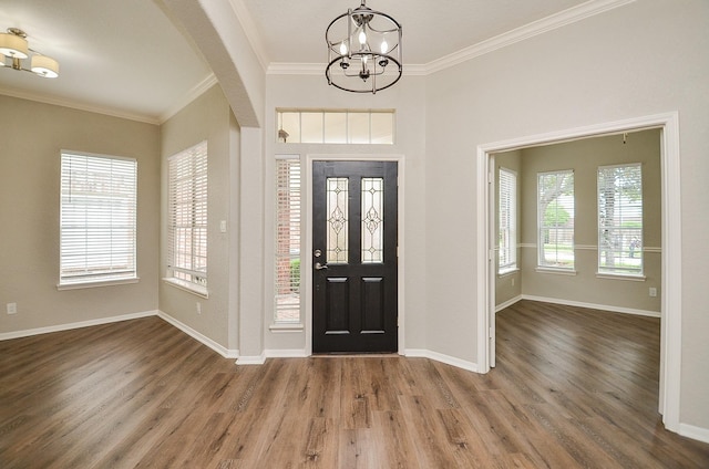 entryway with ornamental molding, wood finished floors, a chandelier, and baseboards