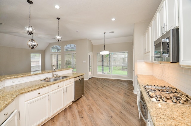 kitchen featuring a sink, stainless steel appliances, backsplash, light wood-style flooring, and white cabinets