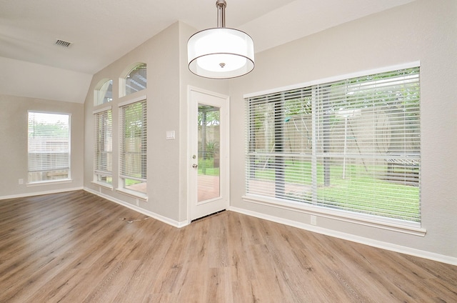unfurnished sunroom with plenty of natural light, visible vents, wood finished floors, and baseboards