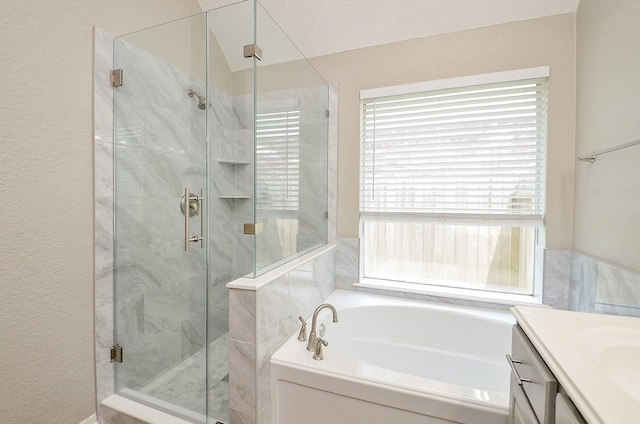 full bathroom featuring a bath, a textured wall, a shower stall, and vanity