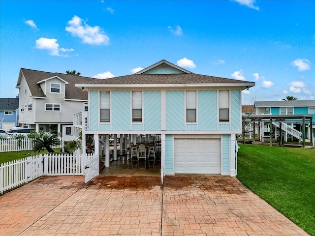 4311 Spanish Main, Jamaica Beach, TX 77554 - view of front of property with fence, decorative driveway, a carport, a front yard, and an attached garage