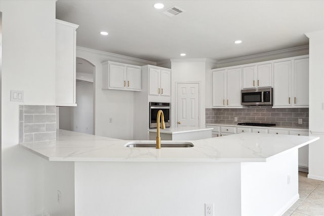 kitchen featuring a sink, a peninsula, light stone counters, ornamental molding, and appliances with stainless steel finishes