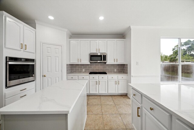 kitchen featuring white cabinetry, ornamental molding, backsplash, and appliances with stainless steel finishes