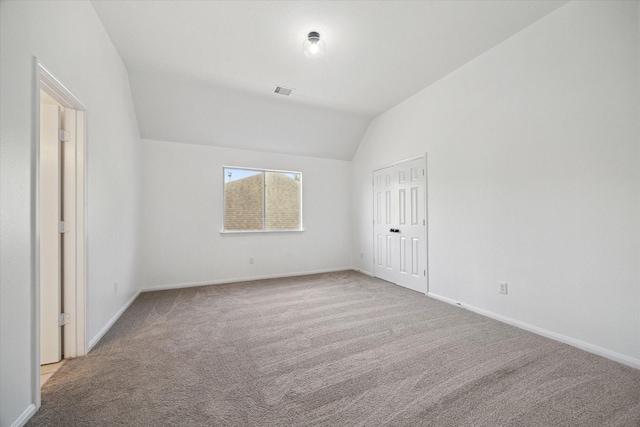 unfurnished bedroom featuring visible vents, carpet flooring, vaulted ceiling, and baseboards