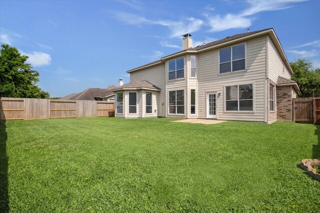 back of house with a lawn, a chimney, a patio, and a fenced backyard